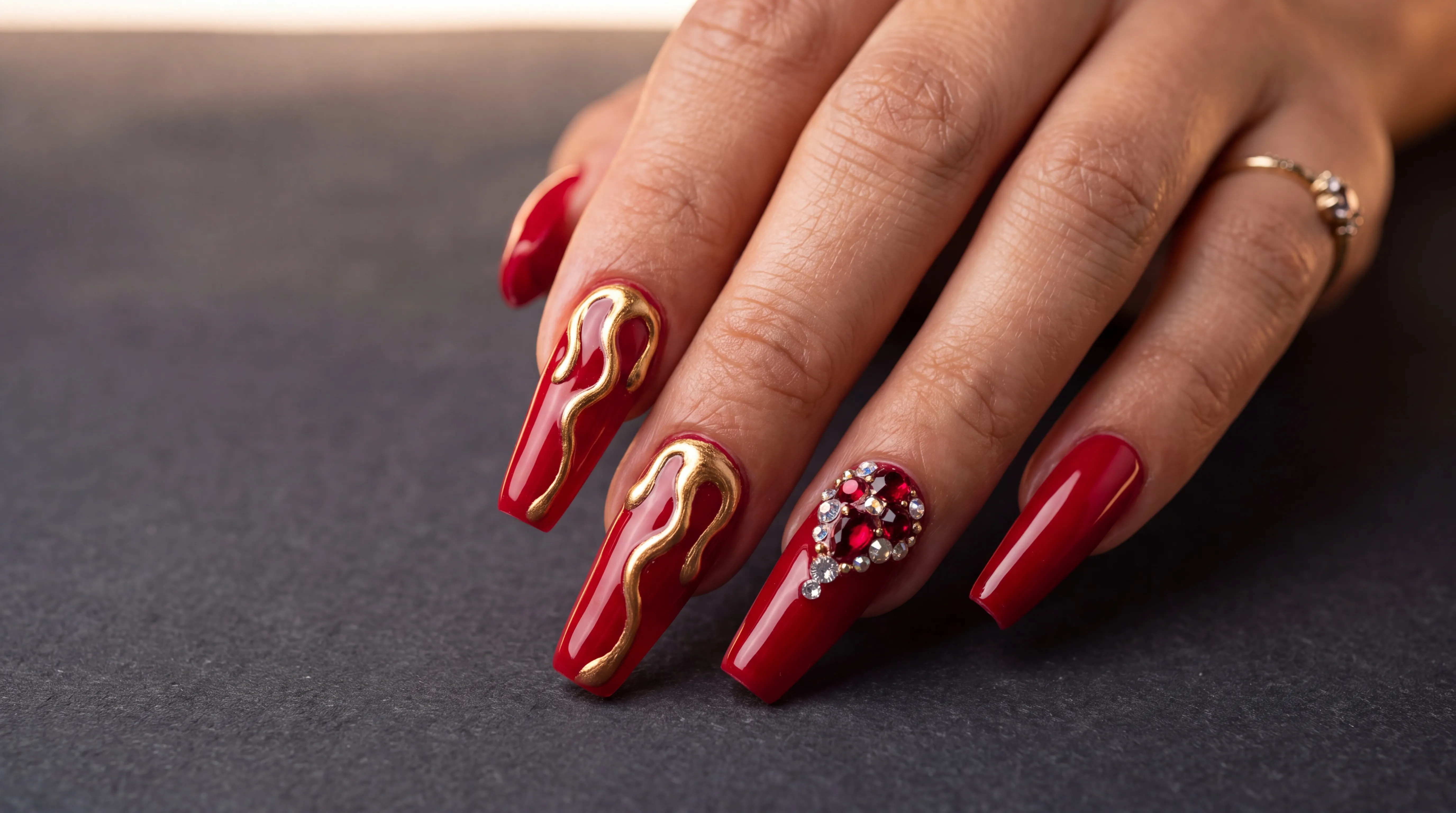 Long coffin nails in cherry red with liquid-gold relief and crystals